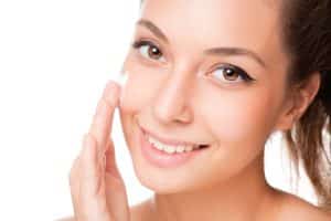 Woman putting lotion on her cheek.